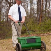 Man in tie and hard hat pushing a lawn mower