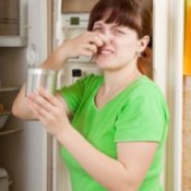 Photo of a woman holding her nose in front of her refrigerator.