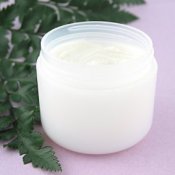 Homemade Moisturizer in a jar near a fern leaf