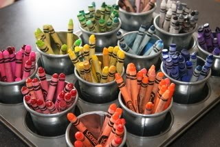 Crayons sorted by color inside small pots in muffin pan.