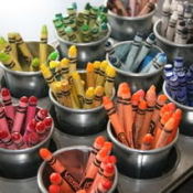 Crayons sorted by color inside small pots in muffin pan.