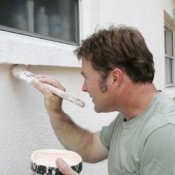 Photo of a man painting his house.