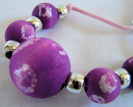 purple and white wooden batik beads strung with gold pony beads
