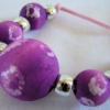 purple and white wooden batik beads strung with gold pony beads