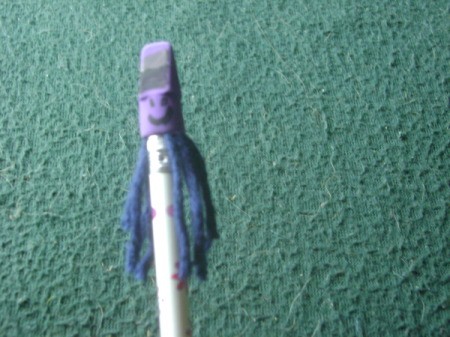 A pencil topper with a funny face and hair.