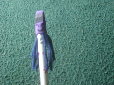 A pencil topper with a funny face and hair.