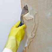 Removing Wallpaper That Has Been Painted, Gloved hand scraping off wallpaper.