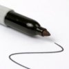 Tip of a Sharpie marker at the end of a squiggly line on white background.
