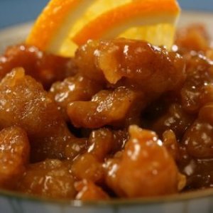 Closeup of Chinese orange chicken with orange slices on top.