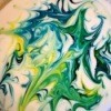 Blue, green, and yellow paint swirled in white milk