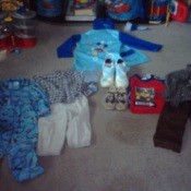 Used children's clothing items laid out on floor