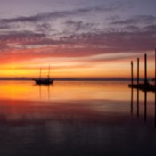 A colorful sunrise over the Puget Sound, with a boat and dock.