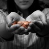 Woman Holding Out Hand Full of Pennies