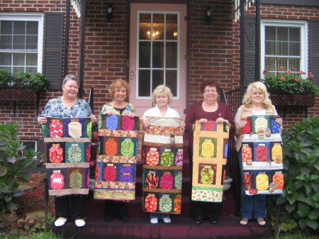 Five women holding finished Mason jar quilts.