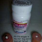 Bottle of Wal-Dryl and two hot dog pieces with pills inserted into holes made by mixer beater.