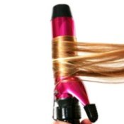 Someone curling hair with a pink and black curling iron.