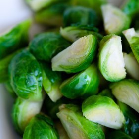 Cut and blanched Brussel sprouts on a white plate.