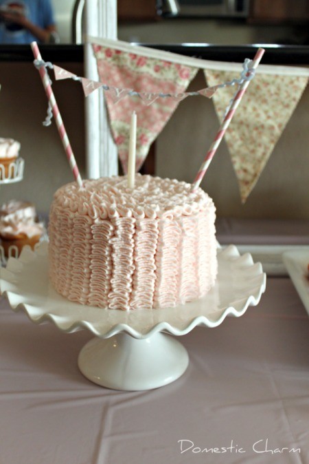 small pink cake with one candle and bunting strung across