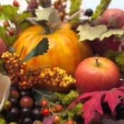 Autumn leaves, pumpkin, apple, and other elements of a fall centerpiece.