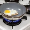 Egg frying in Teflon pan on gas stove.