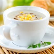 Cup of corn chowder with cheese and bacon on it.