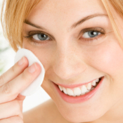 A woman cleaning her face with skin toner.