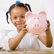 Young girl holding up a pink piggy bank
