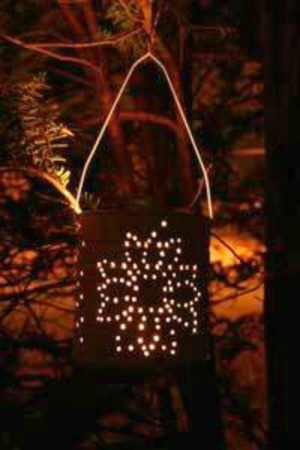 Tin can lantern illuminated with a candle.