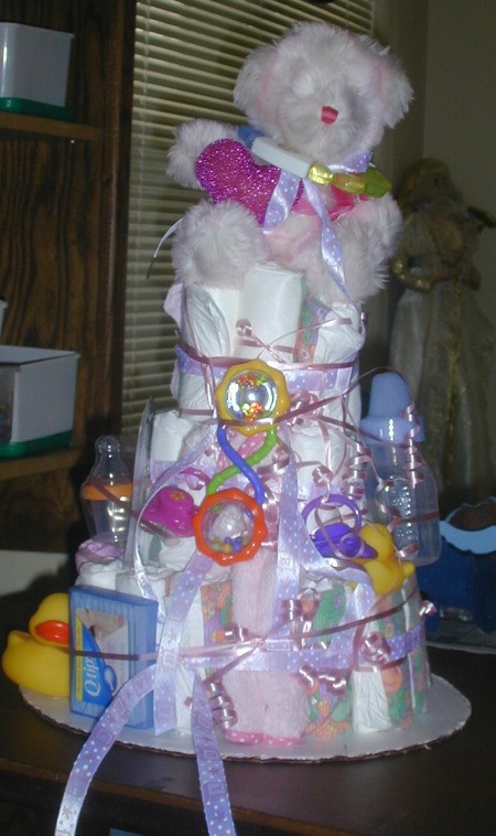 Very tall diaper cake with a white teddy bear on top.