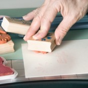 A crafter using rubber stamps to decorate a handmade card.