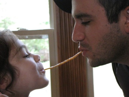Man and Little Girl Eating String of Spaghetti