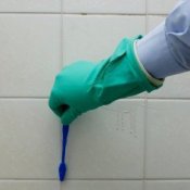 Someone cleaning tile grout with a toothbrush.