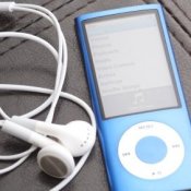 A blue iPod and earbuds on a black leather surface.