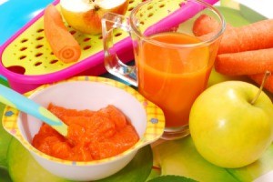 Dish of homemade carrot baby food. It is surrounded by fresh carrots and a ceramic bunny.