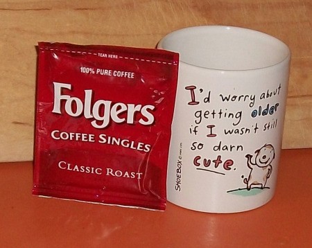 Package of Folger's Singles next to a coffee cup.