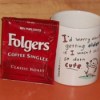 Package of Folger's Singles next to a coffee cup.