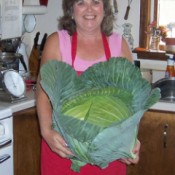 Photo of a woman holding a huge cabbage.