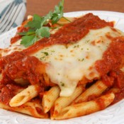 A plate of chicken parmesan on penne pasta, topped with tomato sauce and melted cheese.