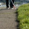 A blind man walking a path with a white cane.