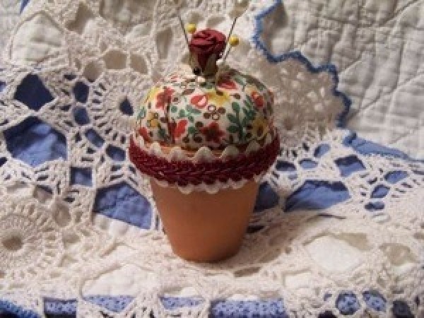 A pincushion made from fabric and a terra cotta pot.