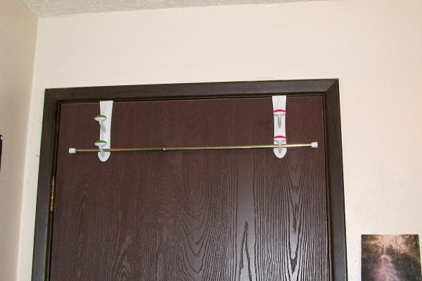 Two over the door hooks holding up a curtain rod.