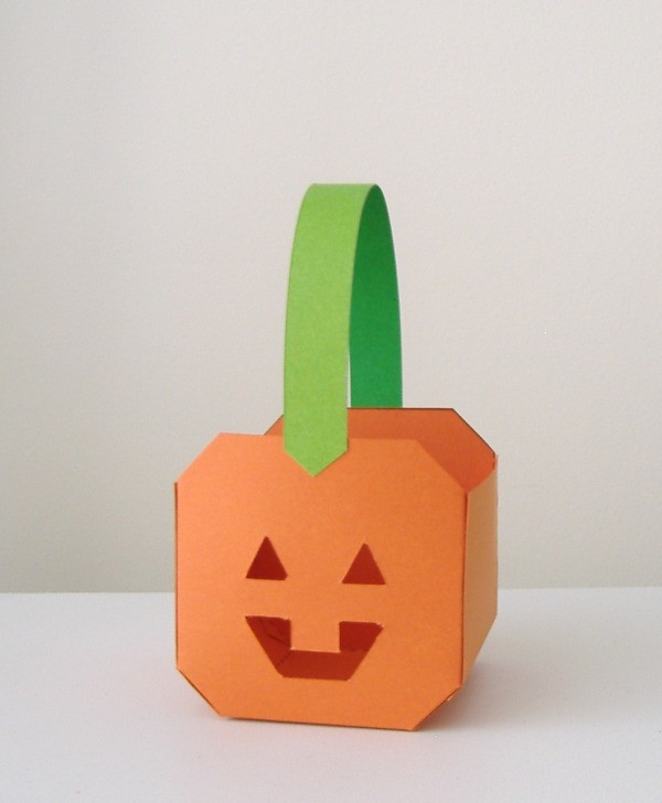 Small paper paper pumpkin basket. Pumpkin is orange, handle is green.