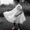 Little Girl Dancing in the Yard With Red Shoes