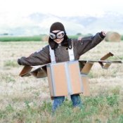 Young Boy Pretending to be a Pilot in Cardboard Plane