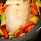 A chicken in a crockpot with veggies.