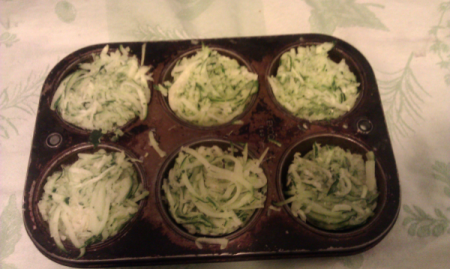 Muffin tin filled with grated zucchini.