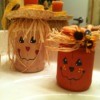 A scarecrow and a pumkin candle holder sitting on a sink.