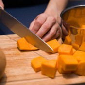 Photo of someone cutting up a pumpkin.