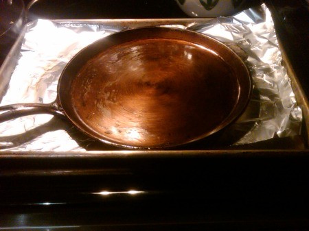 Cast iron griddle sitting on foil in baking pan.