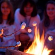Girls roasting marshmallows over a campfire while camping.